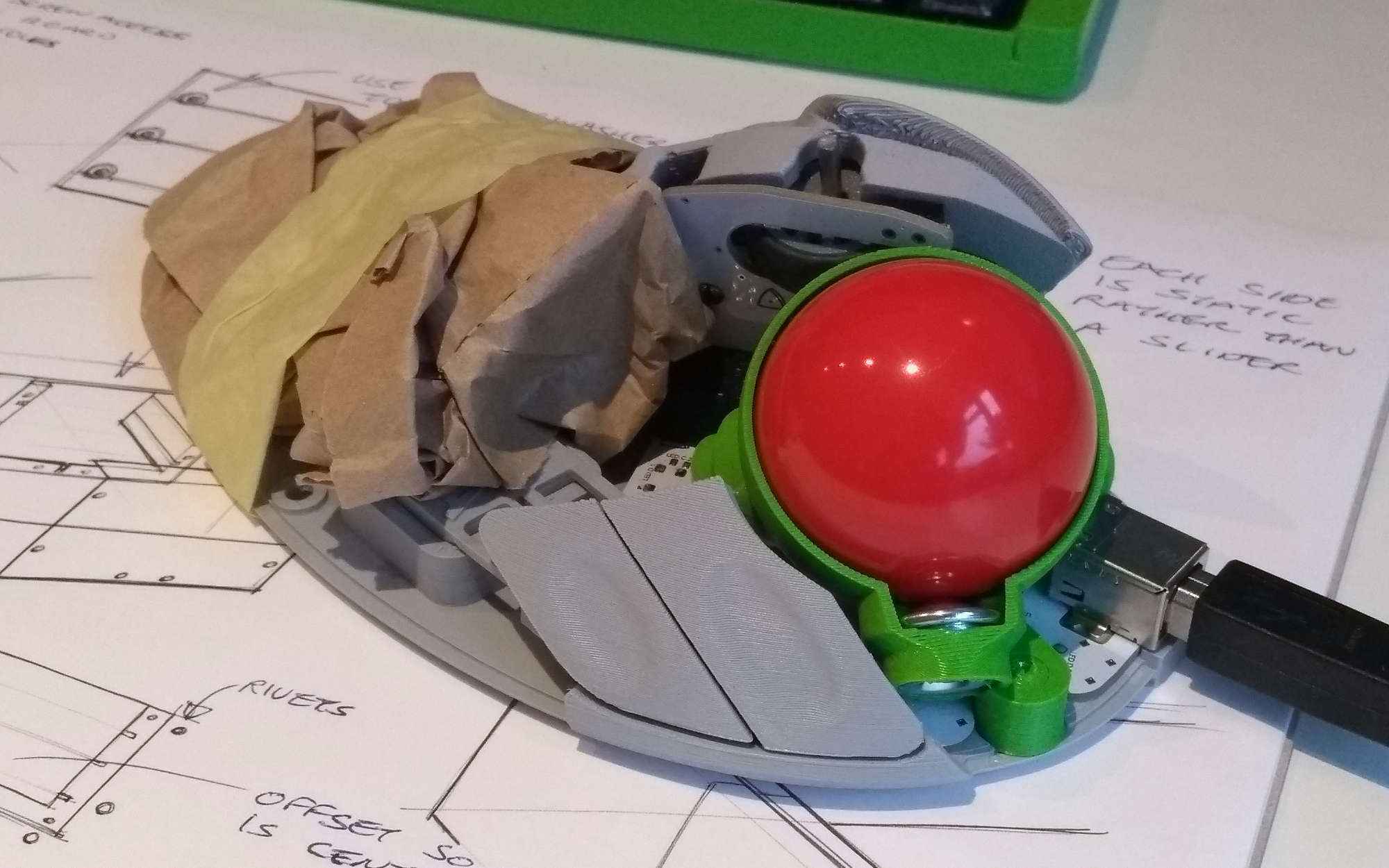 Dodgy-looking prototype BTU holder v2 installed in the Ploopy, with the back half of the mouse formed out of crumpled brown paper