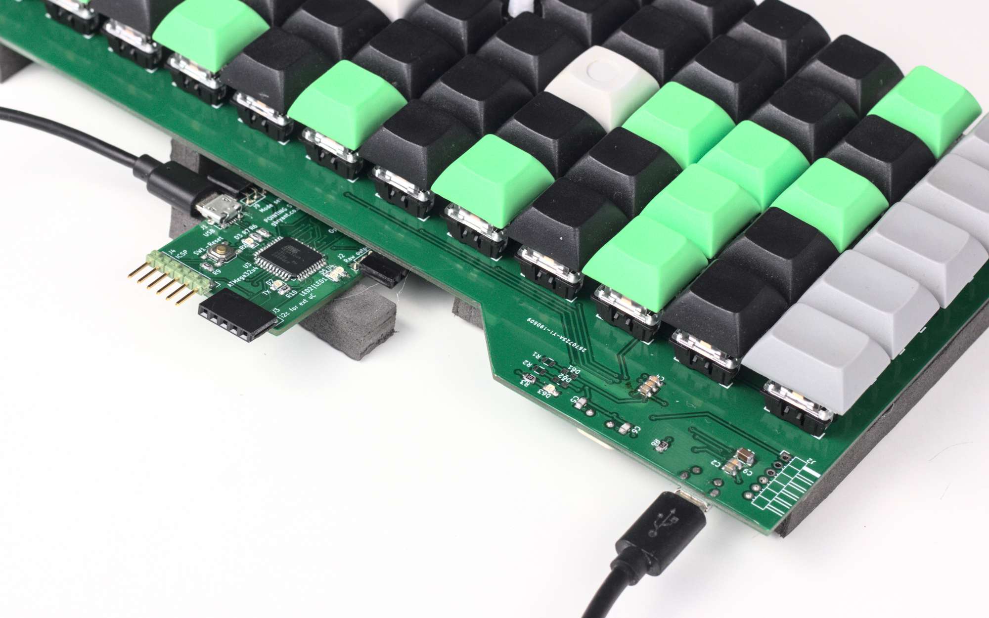A keyboard PCB with keycaps, and another PCB sticking out from underneath
