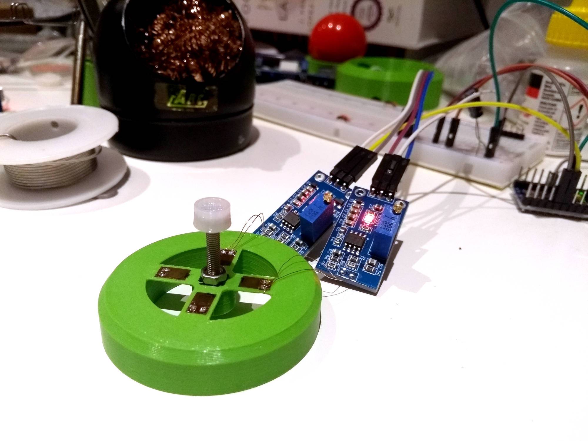 These wires are as easy to damage as they look Close-up of a pointing stick prototype. It's got an outer ring for support, with a plus shape in the middle and a screw sticking up out of the centre. There are four strain gauges glued to the plus shape, with two of them wired to two amplifier PCBs with extremely tiny wires.