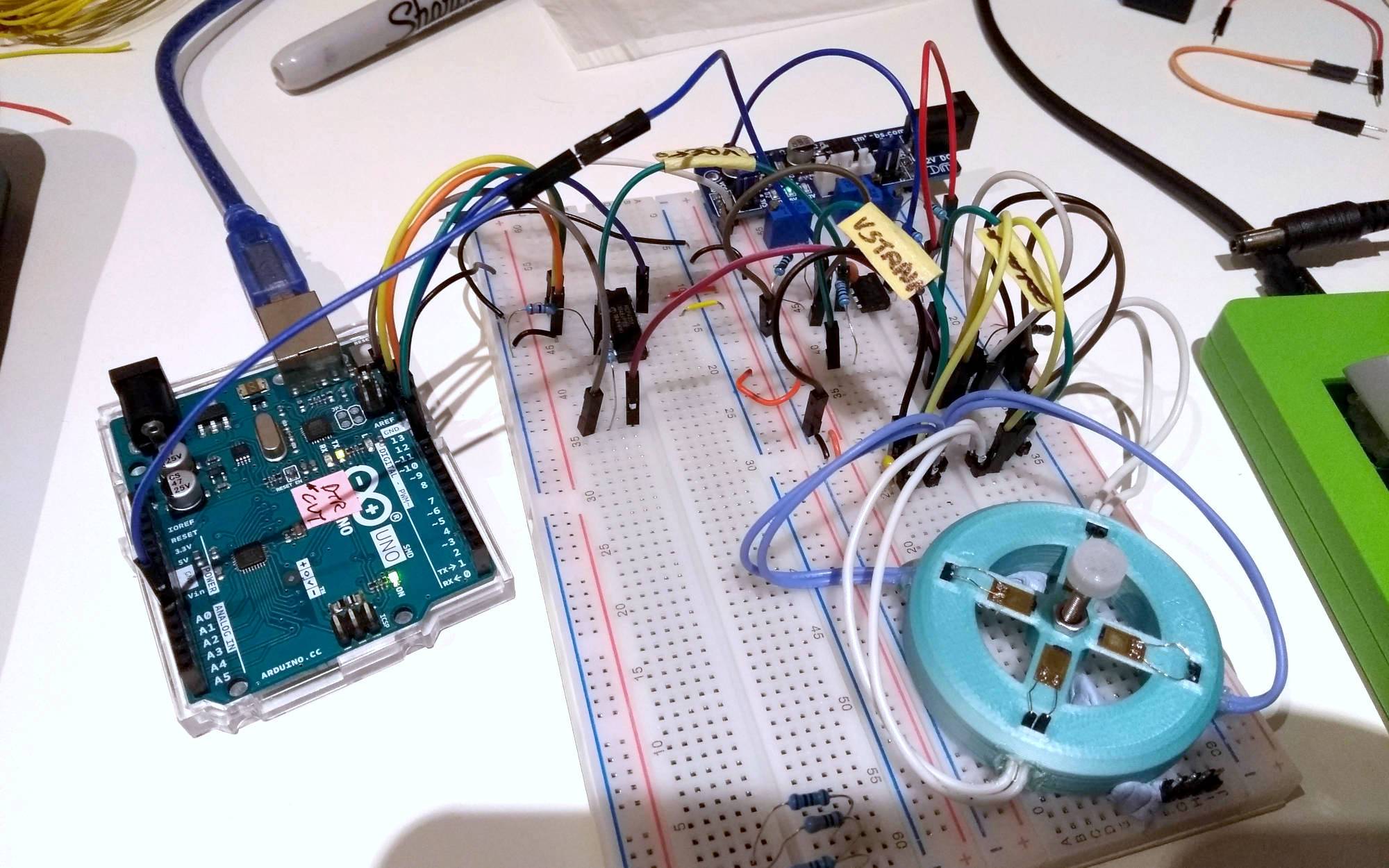 A mess of wires on a breadboard, with the pointing stick prototype on one side and an Arduino on another