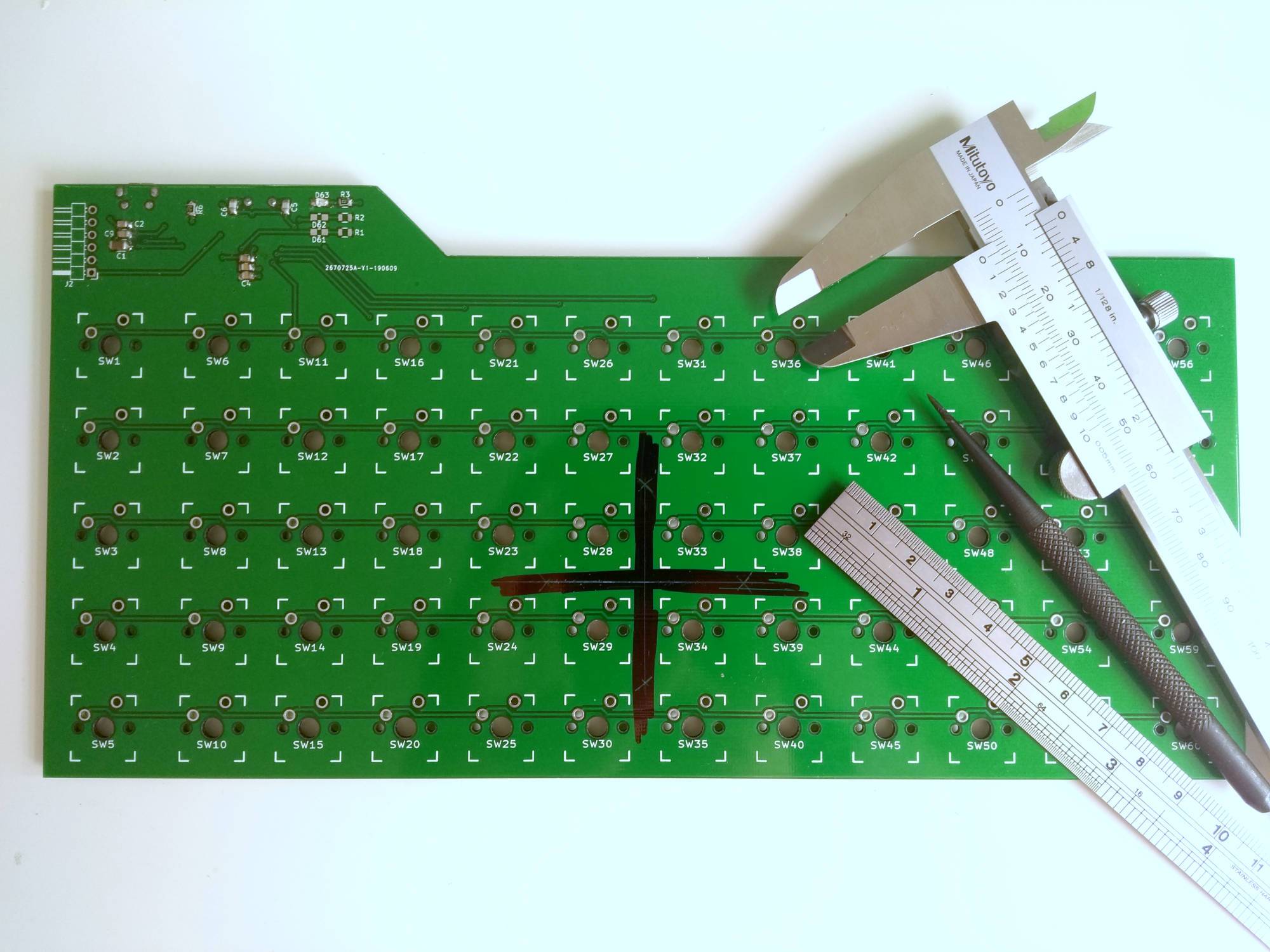 The location of the PCB hole marked roughly with sharpie, and precisely by scratching away the sharpie with calipers and a scriber.