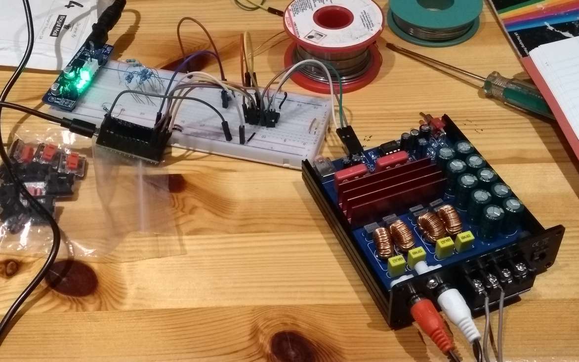 The amp opened up with its volume potentiometer removed. Some wires go from where it was to a digital potentiometer chip on a breadboard. There's a Teensy attached to the breadboard, controlling the digital potentiometer.