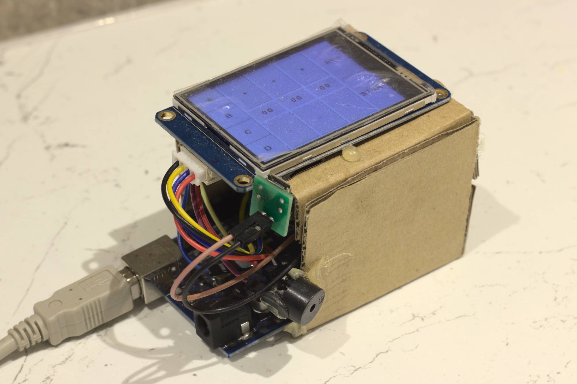 The old prototype - a touch screen held above an Arduino Uno by some cardboard. You can kinda see a load of wires bundled between the two