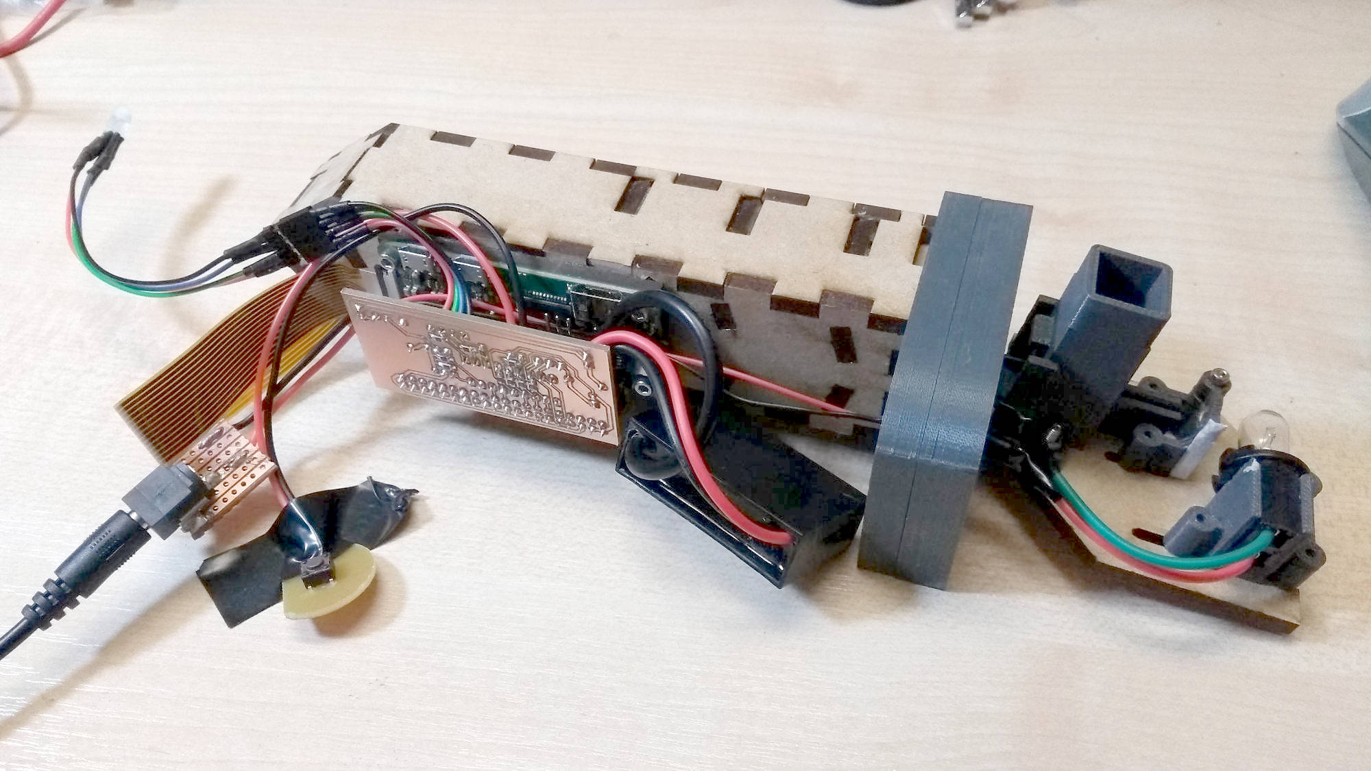 The internals of the spectrometer - an MDF box with a Raspberry Pi mounted to it, various wires going everywhere and a small bulb on the far left.